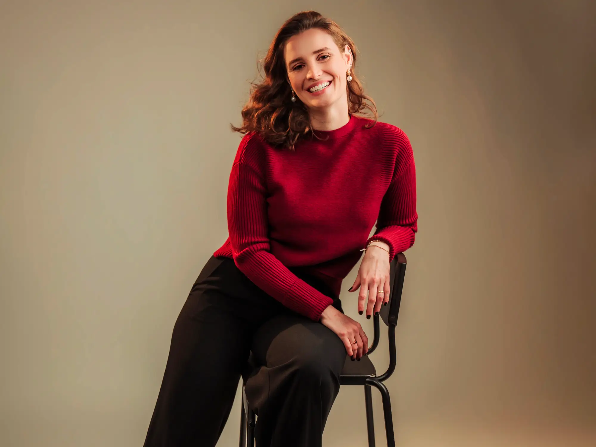 Ana Flávia sentada num divã, a sorrir para a câmara.
