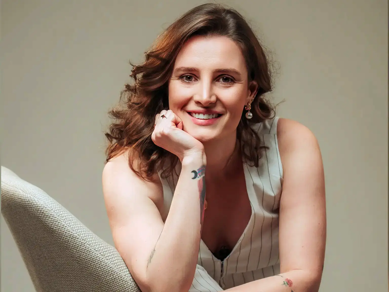 Dra. Ana Flávia Trevizan, sentada num banco alto, a sorrir.