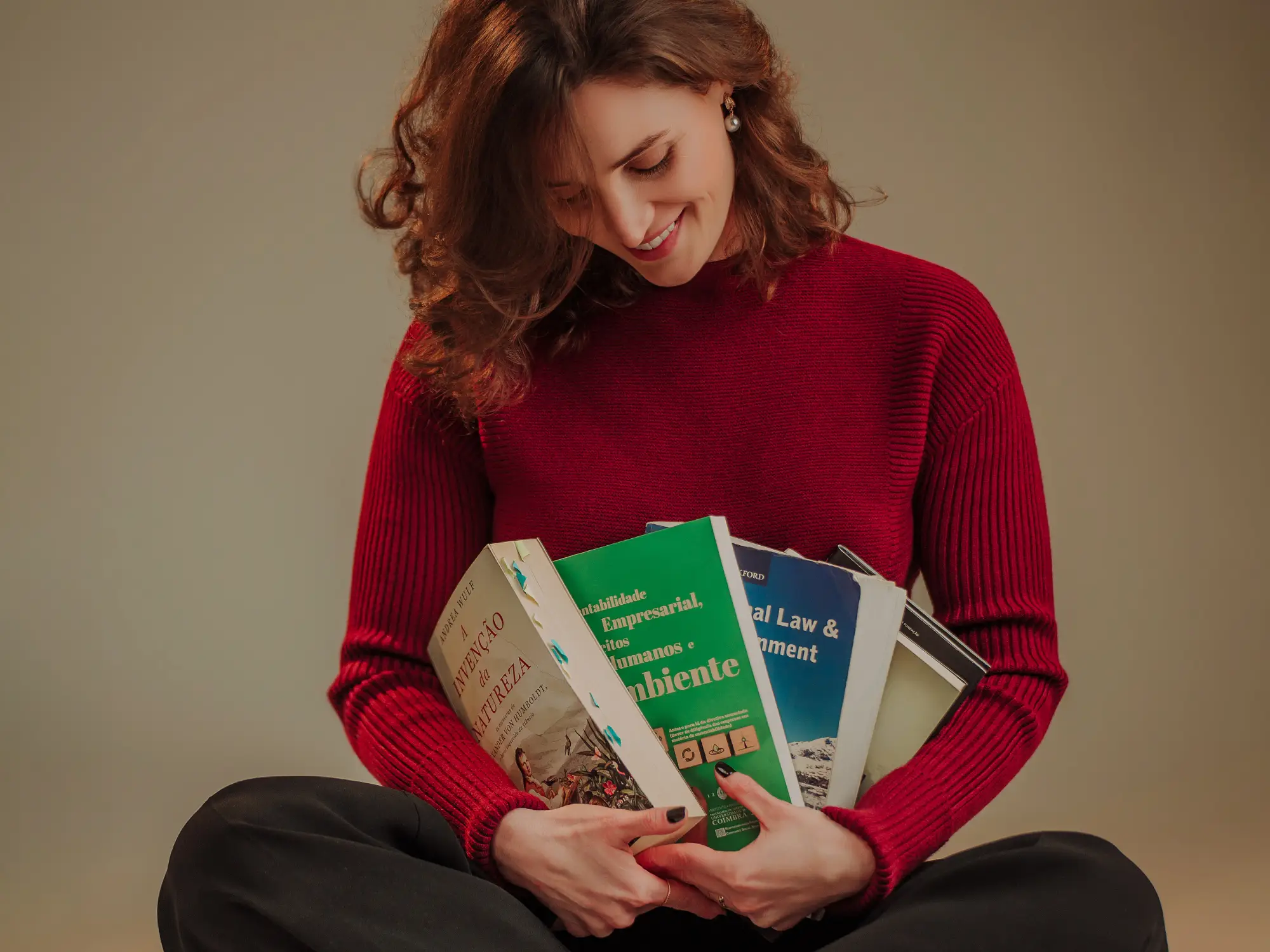 Ana, sentada, segurando livros no regaço.